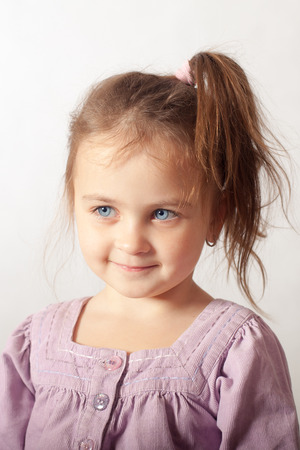 portrait of little blue-eyed girl on a light backgroundの写真素材