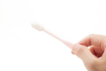 Holding a toothbrrush by hand on white isolated backgroundの写真素材