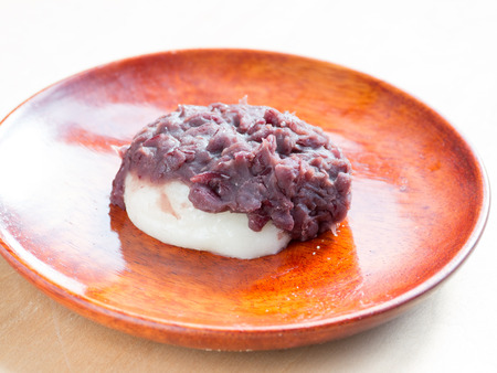 Japanese cuisine, a rice cake with sweet red beans paste on the wooden plateの写真素材