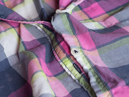Plastic button on a pink, blue, and white checked shirt