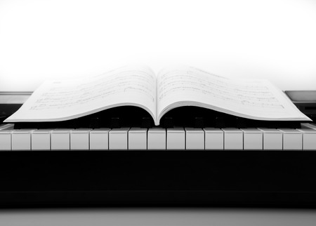 black and white keys of the piano closeup and musical bookの写真素材