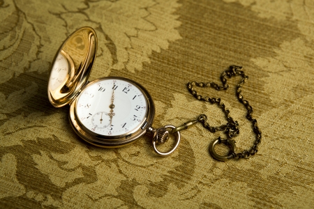 Gold pocket watch on on gold cloth close-upの写真素材