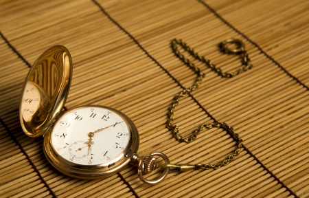 Gold pocket watch on bamboo rugs close-upの写真素材