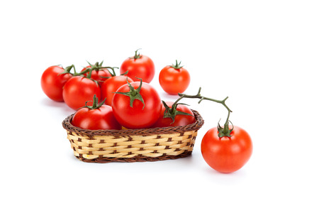 some red tomatoes in a small basket on a white backgroundの写真素材
