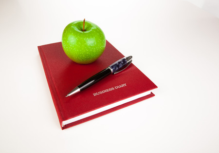 open diary with large pen and green apple on whiteの写真素材