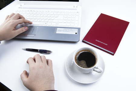 Business still-life comprising business diary, pen, notebook, cup of coffee, human handsの写真素材