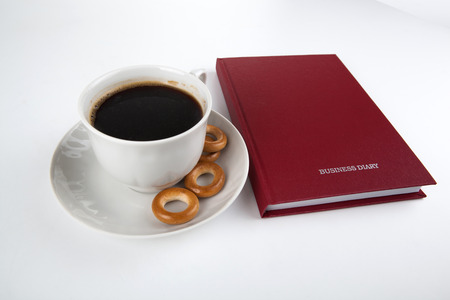 business diary with cup of coffee on a whiteの写真素材