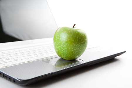 green apple on laptop keyboard on a whiteの写真素材