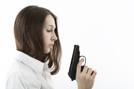 young girl holding a pistol isolated on a white backgroundの写真素材