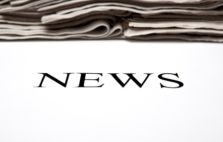 the word news on the background of a stack of newspapers