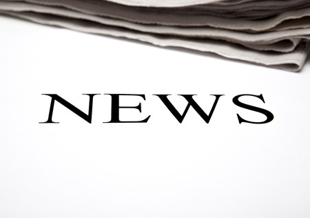 the word news on the background of a stack of newspapersの写真素材