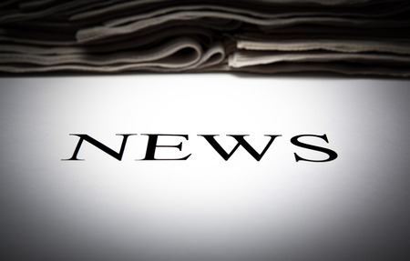 the word news on the background of a stack of newspapers