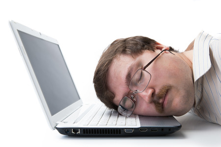 man sleeping on a notebook keyboard at the workplace on a white の写真素材