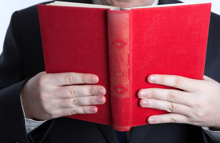 man holding an open red book closeup on a whiteの写真素材