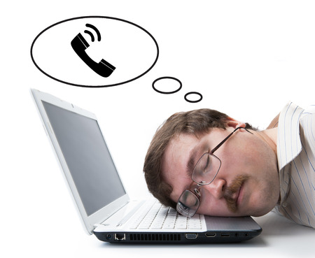 employee at the computer dreaming that he call on a whiteの写真素材