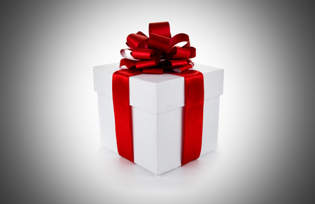 White gift box with red ribbon and bow on grey backgroundの写真素材