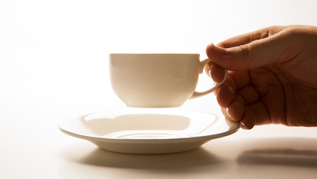 glass cup and saucer in hand closeup on greyの写真素材