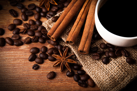 cup of black coffee with roasted coffee and cinnamon sticks closeupの写真素材