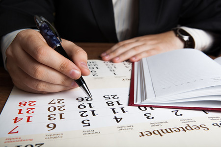 man calculates future plans with calendar close upの写真素材