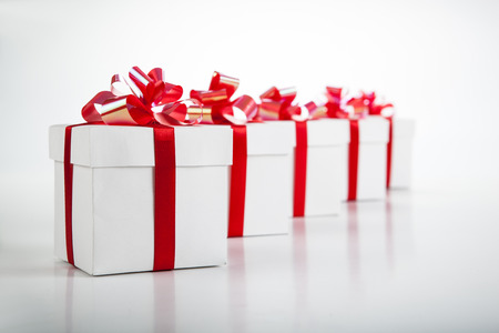 White gift boxes with red ribbons and bows on gray