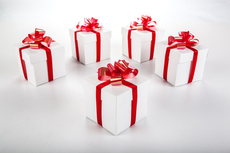 White gift boxes with red ribbons and bows on grayの写真素材