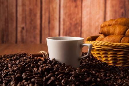 cup with coffee and coffee beans close up on a wood backgroundの写真素材