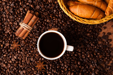 cup with coffee and coffee beans close up on a wood backgroundの写真素材