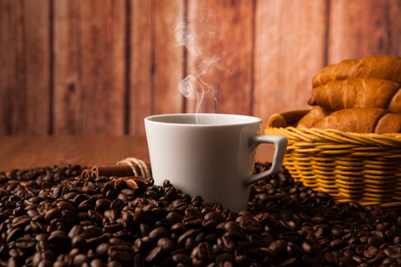 cup with coffee and coffee beans close up on a wood backgroundの写真素材
