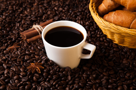 cup with coffee and coffee beans close up on a wood backgroundの写真素材