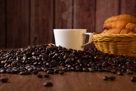 cup with coffee and coffee beans close up on a wood backgroundの写真素材