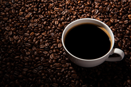 a cup of black coffee and roasted coffee beans close upの写真素材