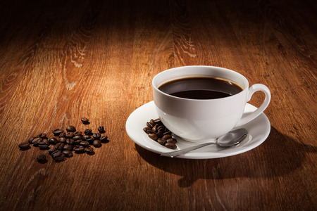 a cup of black coffee and roasted coffee beans close upの写真素材