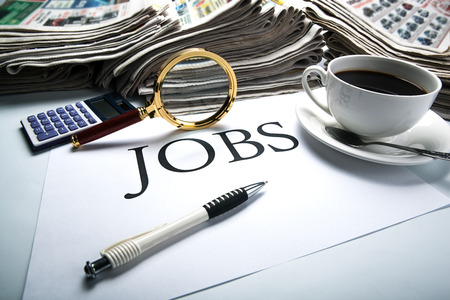 title jobs with loupe, pen, newspapers, cup of coffee and calculatorの写真素材