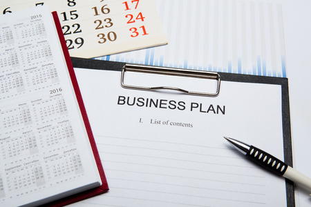 Document with title business plan and office suppliesの写真素材