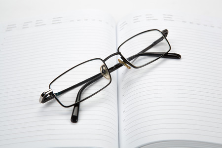 Business diary with eyeglasses on a whiteの写真素材