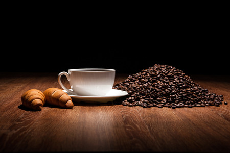 cup of coffee and roasted beans with croissantsの写真素材