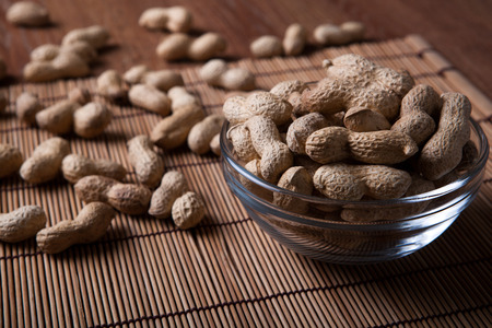 large grains of peanuts in the shell and the bowl close up