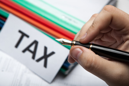 pen in hand and metaphor for the payment of taxesの写真素材