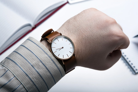 Workplace businessman looks at the clock and office toolsの写真素材