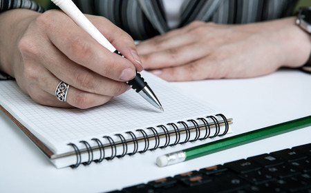 diary and human hand holding a pen close-up