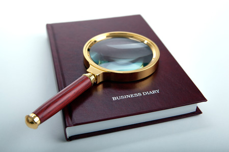 magnifier lies on a business diary on a white table close upの写真素材