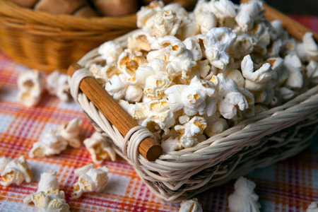 salted popcorn in a wicker basket on a napkin close upの写真素材
