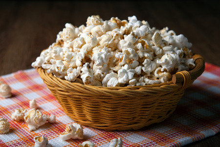 salted popcorn in a wicker basket on a napkin close upの写真素材