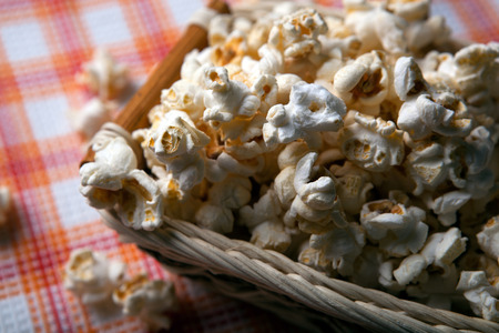 salted popcorn in a wicker basket on a napkin close upの写真素材