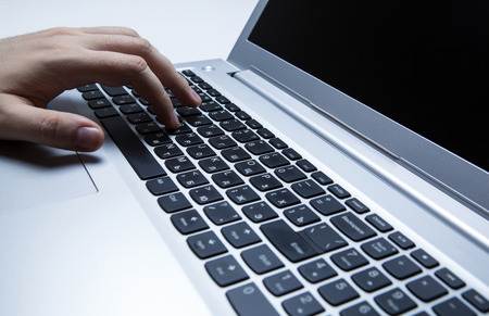 man is typing on a laptop keyboardの写真素材