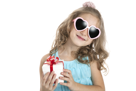 portrait of a little girl in pink sunglasses with gift box on a white backgroundの写真素材