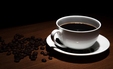 cup of coffee and beans on the wooden table on a black backgroundの写真素材