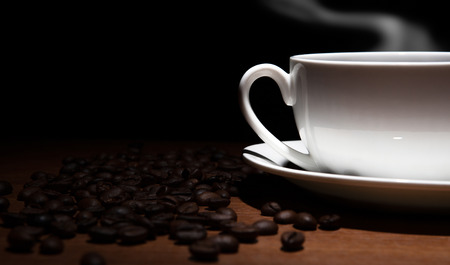 cup of coffee and beans on the wooden table on a black backgroundの写真素材