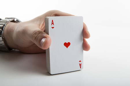 Human hand holding the ace of hearts and a deck of cards close upの写真素材