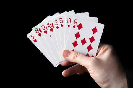 male hand holding a fan of playing cards on a black backgroundの写真素材